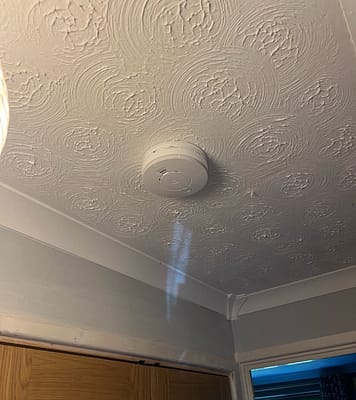 Electrician installing and testing fire safety equipment. Emergency electrician testing smoke alarms in Milton Keynes