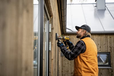 Electrician in high-vis repairing a consumer unit during an emergency call-out. Emergency electrician repairing outdoor security light Milton Keynes